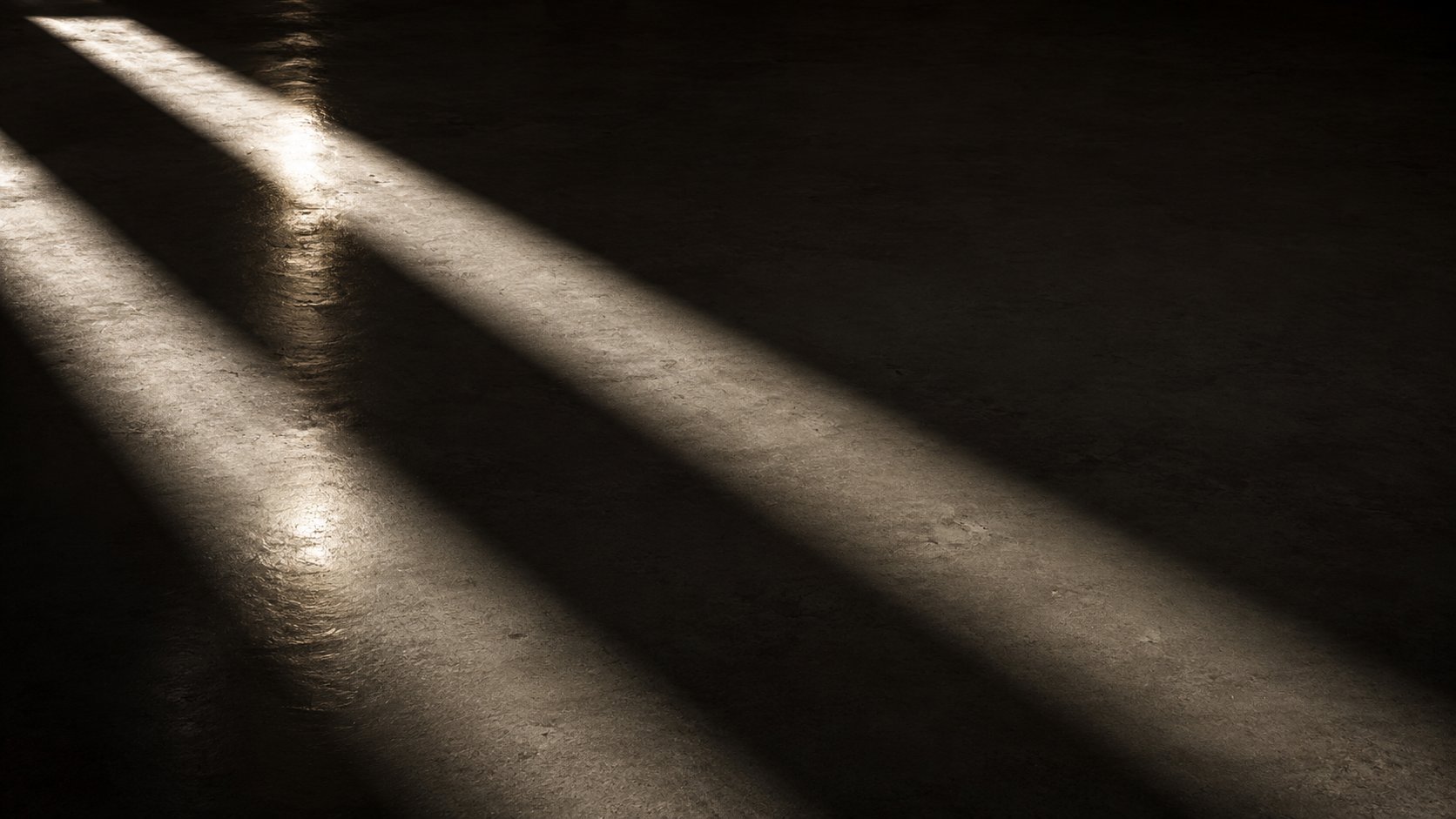 Two beams of light cutting across a dark, textured floor
